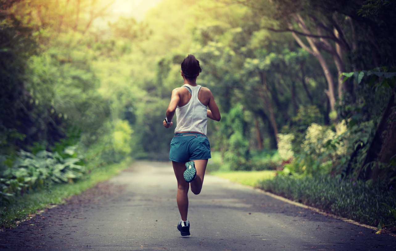 Coureur féminin courant au sentier de parc d'été. Femme de forme physique saine faisant le jogging à l'extérieur.