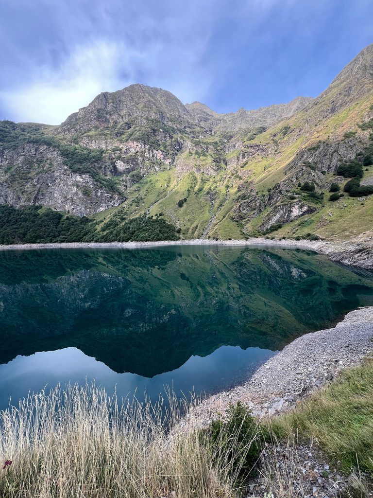Lac de montagne aux eaux calmes reflétant les sommets environnants, lieu de ressourcement et d’équilibre intérieur