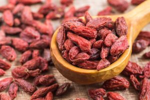 Baies de Goji dans une cuillère en bois, en gros plan, superaliment utilisé dans la cuisine, offrant de nombreux avantages pour la santé